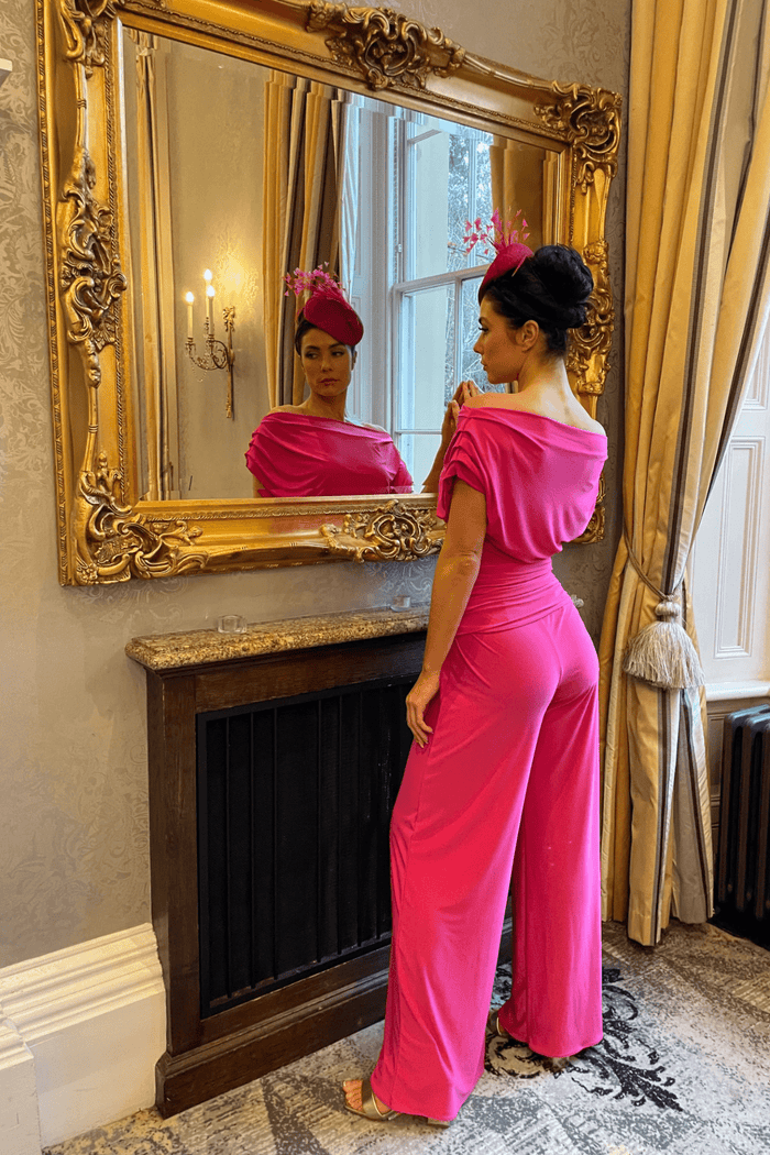 Woman wearing ATOM LABEL Carbon Jumpsuit in Hot Pink by ATOM LABEL, standing by mirror, shop ATOM LABEL at Dotique.