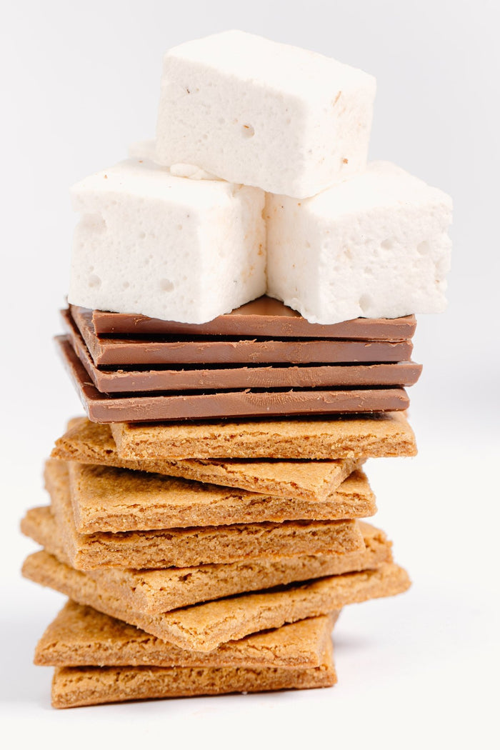 A stack of gluten free XO marshmallow graham crackers with chocolate bars on top and homemade vanilla marshmallows on top of that