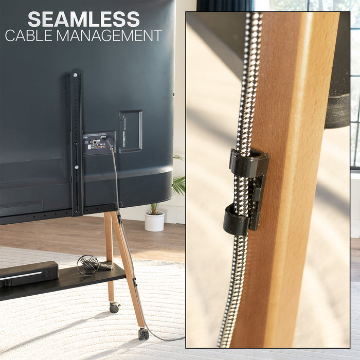 A cable management clip holding a braided black and silver cable next to a wooden furniture frame, with a TV stand and TV in a room shown in the background and the text 'SEAMLESS CABLE MANAGEMENT' at the top.