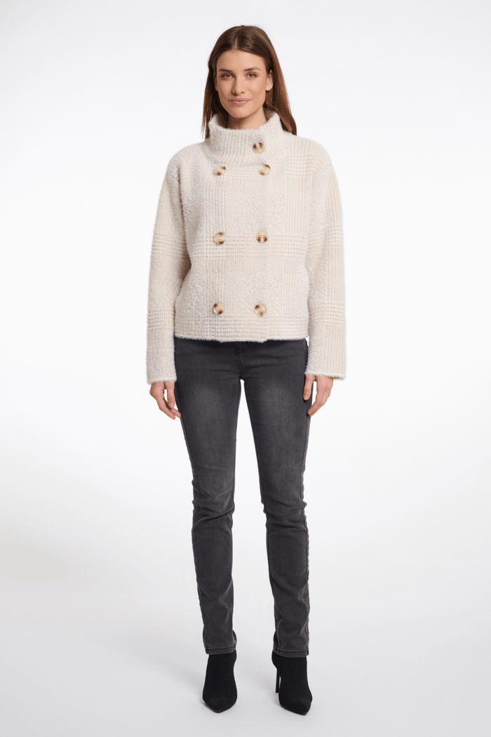 Woman wearing a cream knitted cardigan with gold buttons on a white background