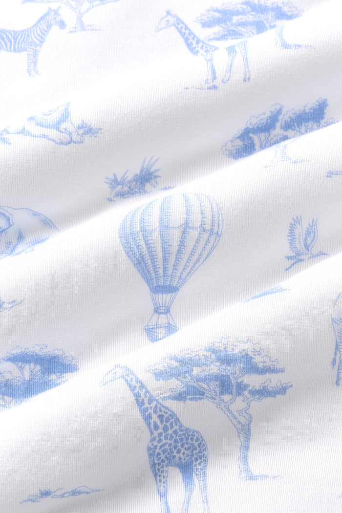 Close up of bamboo fabric: A dusty blue toile print on a white background, featuring hot air balloons, lions, giraffes, elephants, and flying birds, all among patches of grass, trees, bushes, and rocks.