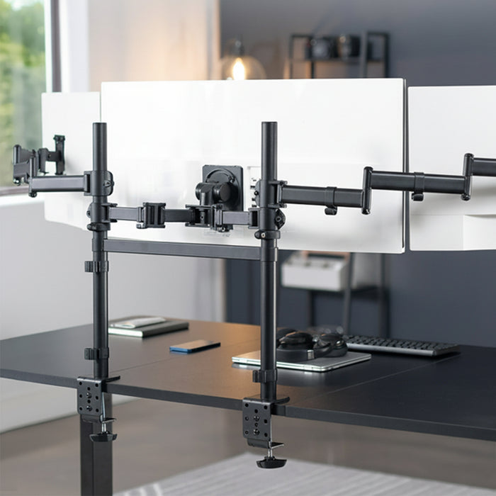 Multiple computer monitors on a desk with a monitor stand in an office setting.