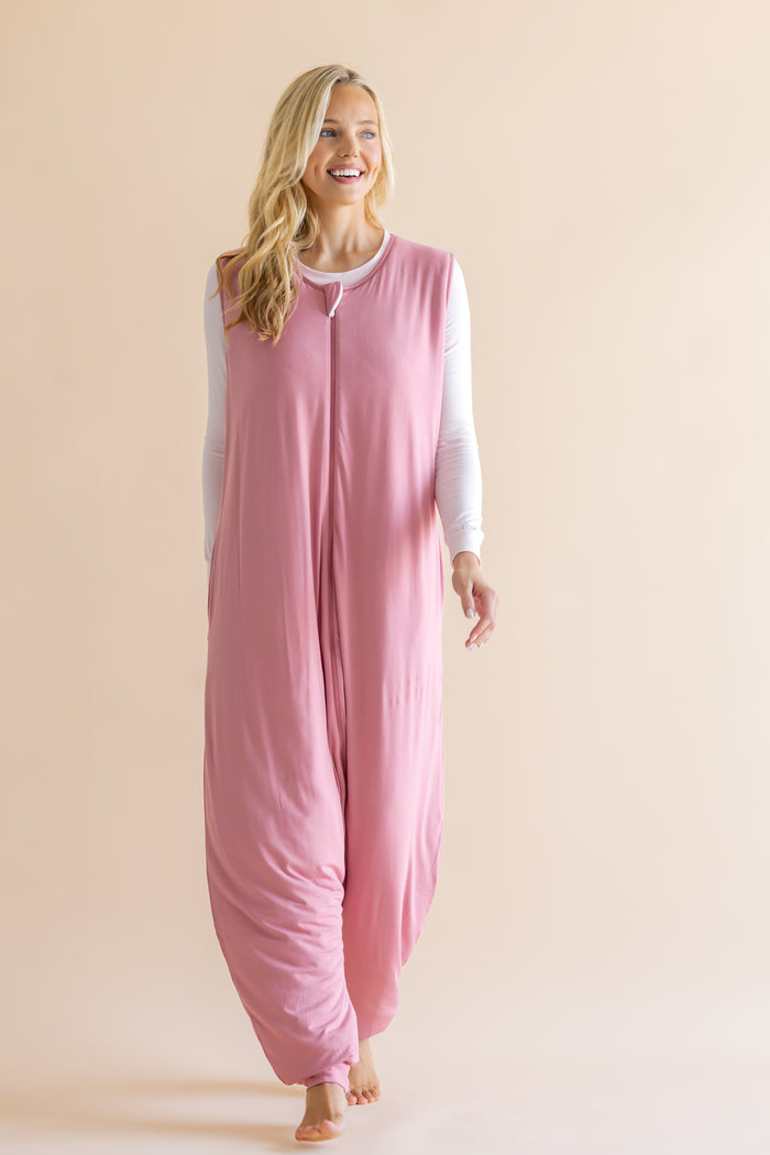 Woman wearing a pink onesie against a beige background