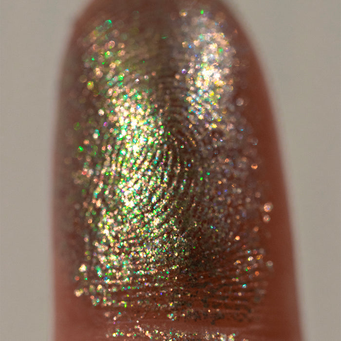 Close-up finger swatch of the eyeshadow Alloy on medium skin tone.