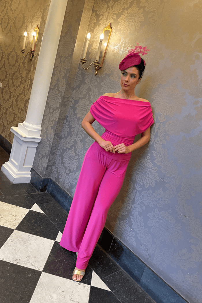 Woman wearing a bright pink ATOM LABEL Carbon Jumpsuit in Hot Pink, styled with a matching hat, shop ATOM LABEL at Dotique