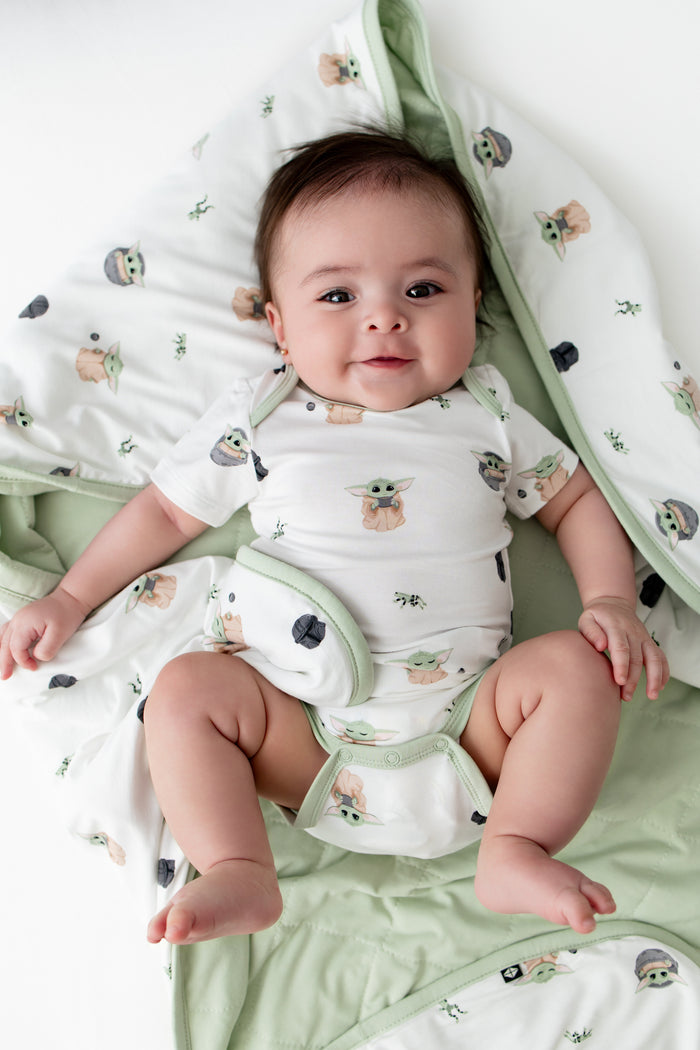 Close up of infant laying on a Baby Blanket in Grogu™ wearing a matching short sleeve bodysuit