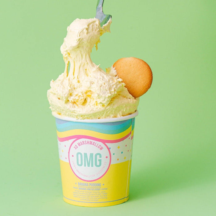 A spoon digging into a cup of yellow ooey marshmallow goodness with a banana flavor, accompanied by a gluten-free Nilla Wafer.