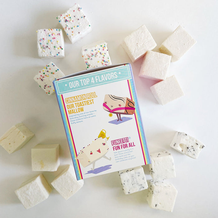 Funfetti, Cinnamon Roll, Salted Caramel and Chocolate Chip marshmallows laid out around the side of the XO Marshmallow Best of the Best variety pack packaging that features a cute drawing of cinnamon roll marshmallows and funfetti marshmallows.