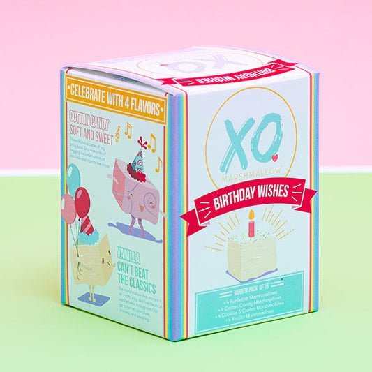 A small illustrated product box standing upright on a pastel green surface against a pink background. The box has colorful graphics, including a large 'XO' logo and birthday-themed illustrations.