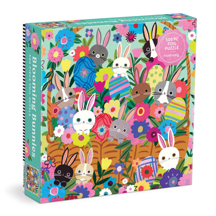 The Tara Lilly Blooming Bunnies 500 Piece Foil Family Puzzle features illustrated bunnies, patterned eggs, vibrant flowers, and metallic foil accents on a teal background for a shiny, colorful puzzling experience.