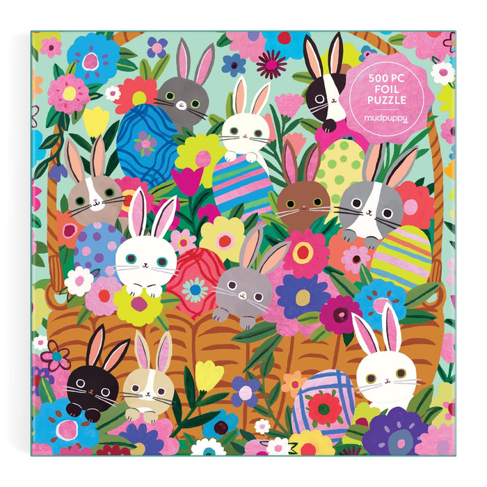 Charming cover art by Tara Lilly features bunnies with big eyes among Easter eggs and flowers, set against green leaves. This illustration appears on the Blooming Bunnies 500 Piece Foil Family Puzzle.