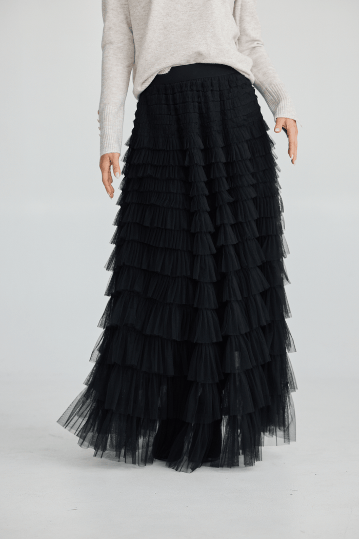 Black tiered skirt worn by a person on a white background