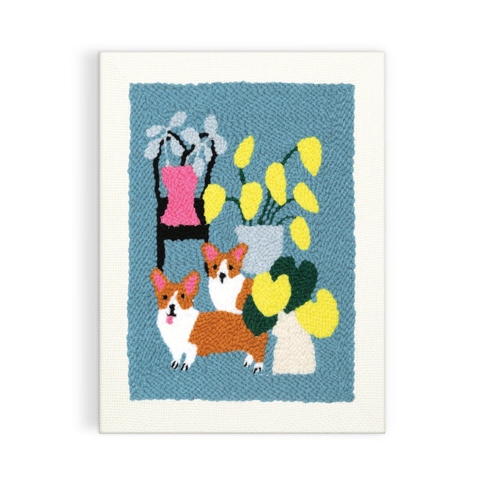 The Anne Bentley Corgi Friends Punch Needle Kit features an embroidered artwork of two brown and white corgis, a black chair with a pink cushion, and vases with colorful leaves on a blue background.