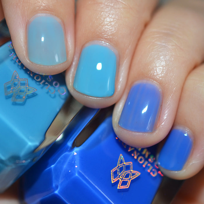Close-up of nails painted with Cumulus Nail Lacquer on fair skin tone. Hand is holding polish bottle.