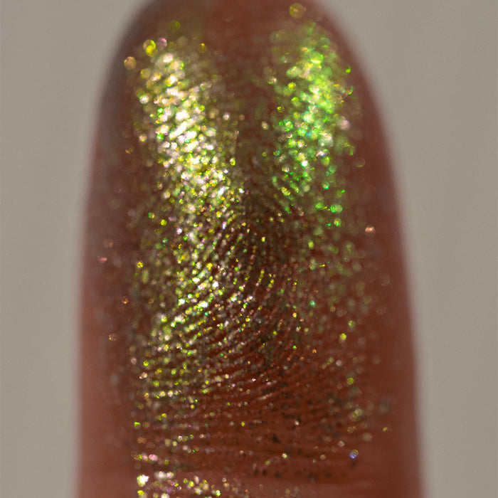 Close-up finger swatch of the eyeshadow Electron on medium skin tone.