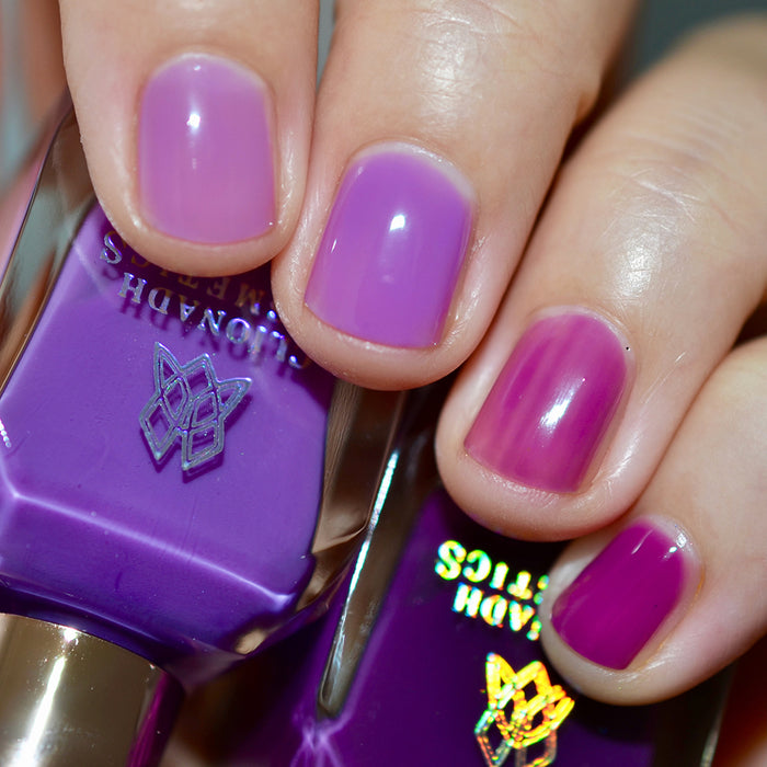 Close-up of nails painted with Euphoric Nail Lacquer on fair skin tone. Hand is holding polish bottle.