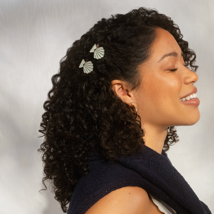 Model with curly hair wearing Kitsch Gold & Pearlized Cream Metal Clam Shell Clips – 2 clips styled together