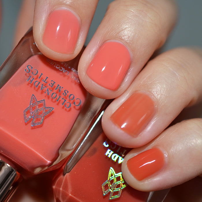 Close-up of nails painted with Horizon Nail Lacquer on fair skin tone. Hand is holding polish bottle.