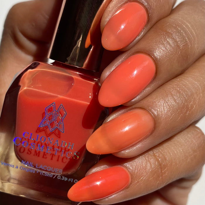 Close-up of nails painted with Horizon Nail Lacquer on medium skin tone. Hand is holding polish bottle.