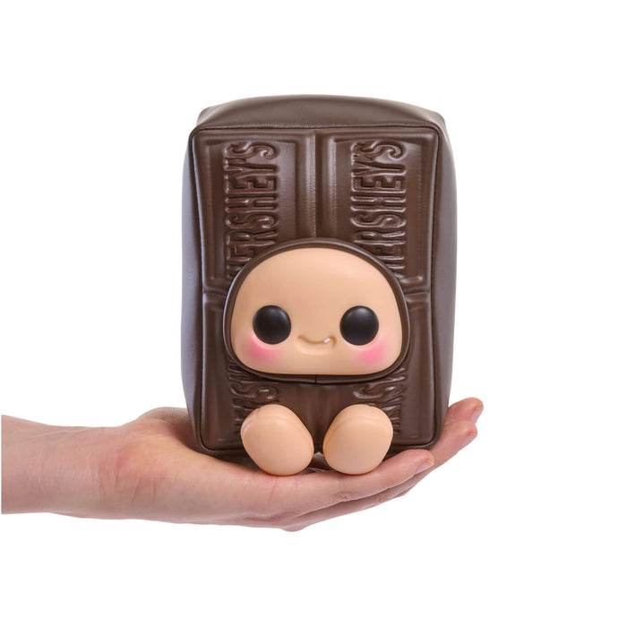 Stuffed toy shaped like a Hershey's bar with a face held in a hand on a white background