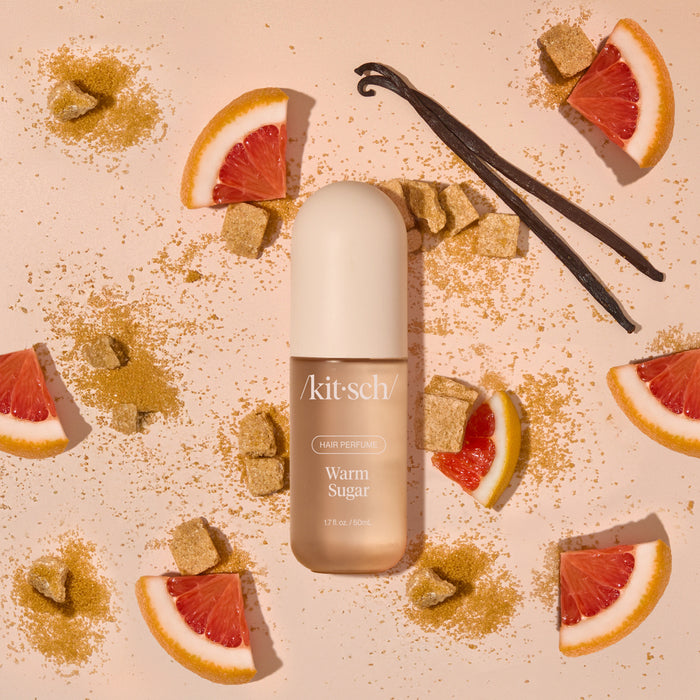 Model misting Kitsch Warm Sugar Hair Perfume onto long, smooth hair