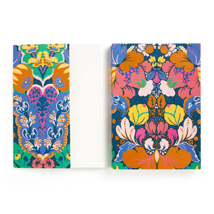 The Liberty Glastonbury Premium A5 Notebook by Liberty London features vibrant orange, blue, green, and pink floral and botanical covers. The inside is blank and white, contrasting elegantly with its colorful decorative exterior.