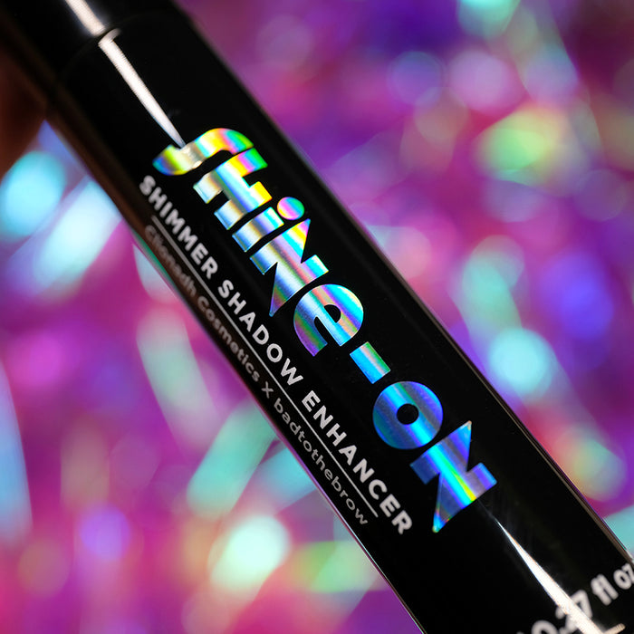 Close-up of the Shine-On Shimmer Shadow Enhancer bottle, on a colourful blurred background.