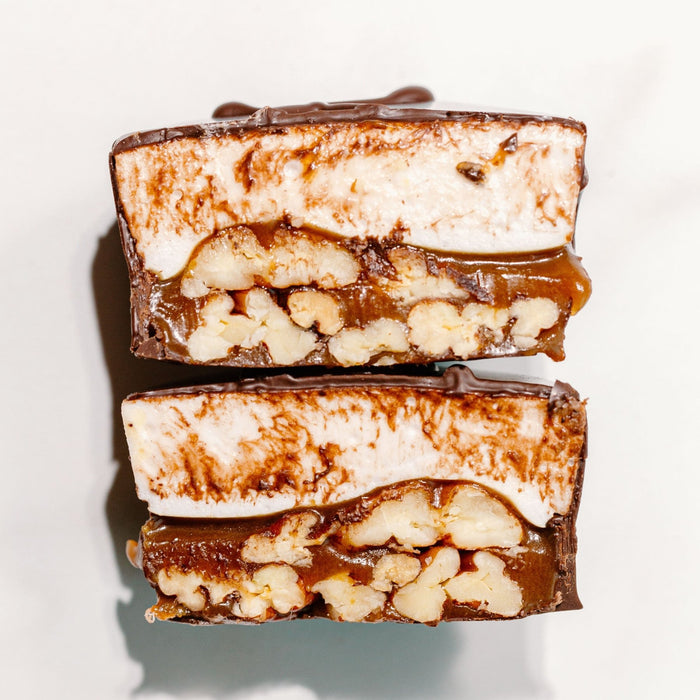 A cross section of a marshmallow turtle candy against a white background. It shows caramel, pecans and vanilla homemade marshmallow