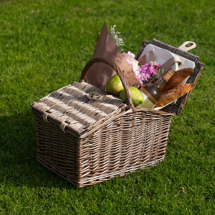 Picnic basket full of food, flowers and a bottle of wine