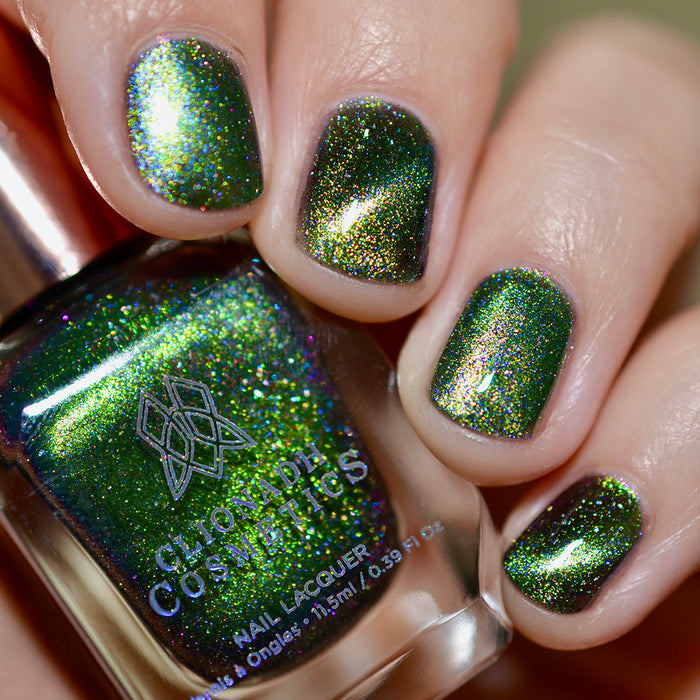 Close-up of nails painted with Planetary Attraction Nail Lacquer on fair skin tone. Hand is holding polish bottle.