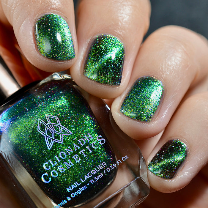 Close-up of nails painted with Planetary Attraction Nail Lacquer on fair skin tone. Hand is holding polish bottle.
