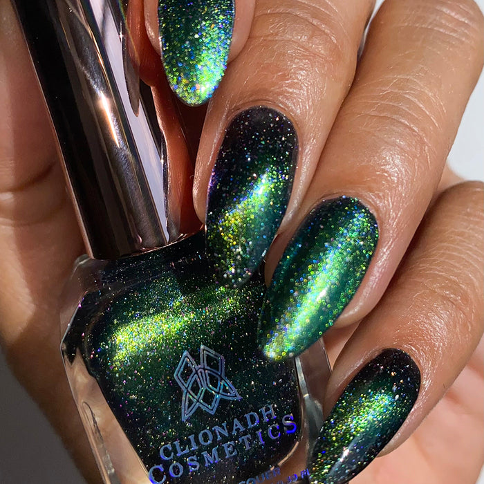 Close-up of nails painted with Planetary Attraction Nail Lacquer on medium skin tone. Hand is holding polish bottle.