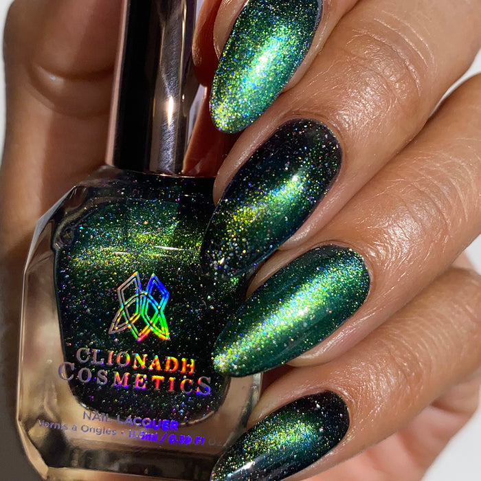 Close-up of nails painted with Planetary Attraction Nail Lacquer on medium skin tone. Hand is holding polish bottle.