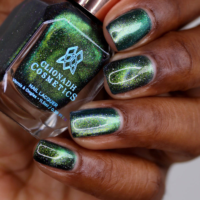 Close-up of nails painted with Planetary Attraction Nail Lacquer on deep skin tone. Hand is holding polish bottle.