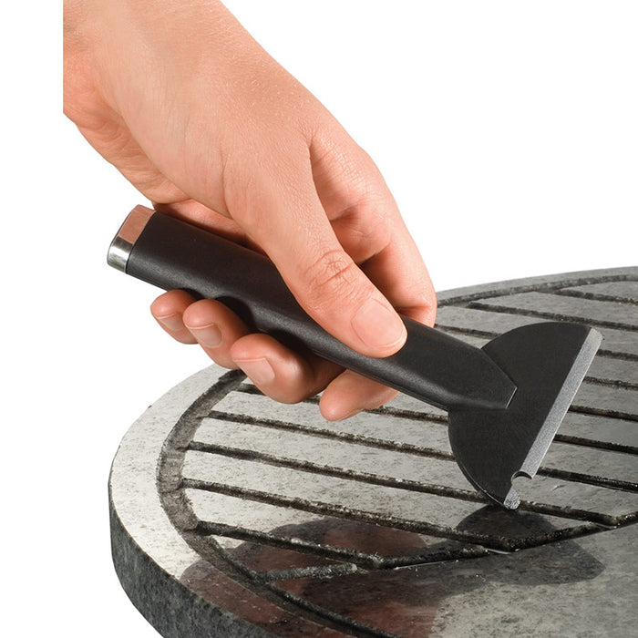 Eine Hand verwendet das Unold Raclette Multi 4 in 1 zum Reinigen der Roste eines runden Grills.