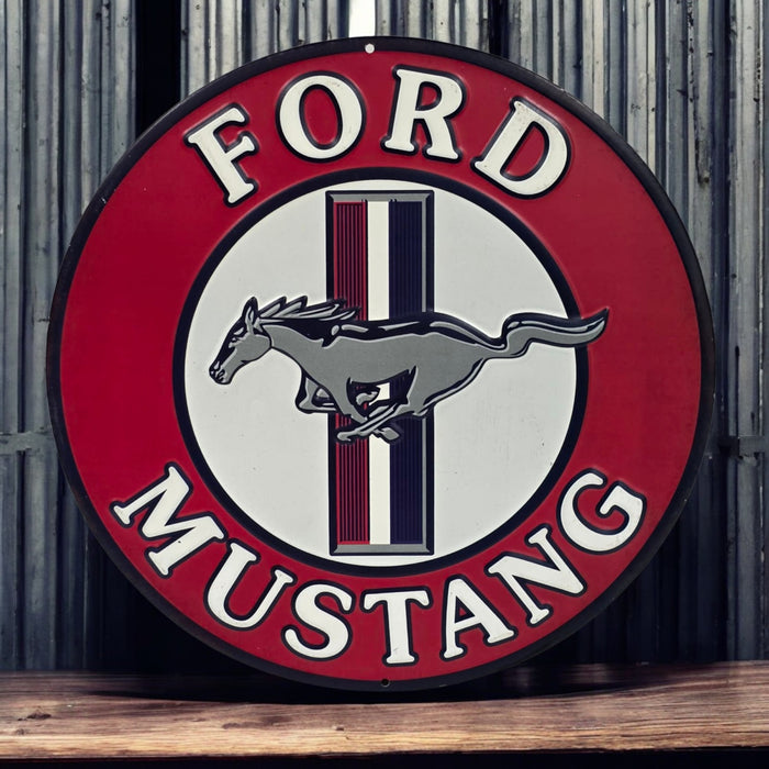 Ford Mustang logo on a round sign with a red border and wooden surface below