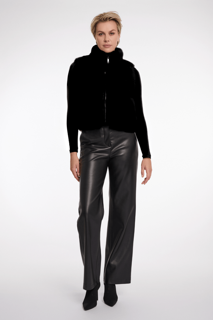 Person wearing a black jacket and leather pants on a white background