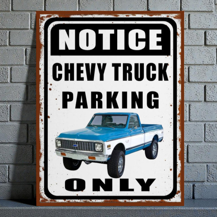 Vintage-style metal sign with a blue and white Chevy truck and text 'Notice Chevy Truck Parking Only' on a brick wall background.