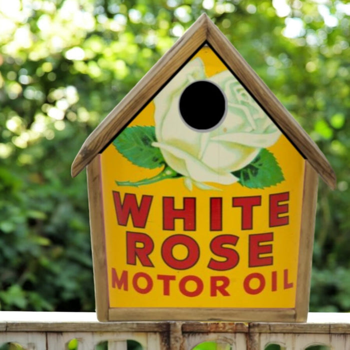 Birdhouse with White Rose Motor Oil branding against a blurred green background