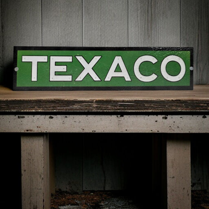 Vintage Texaco sign on a wooden surface with a wooden panel background