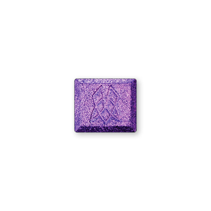 A single multichrome eyeshadow in colour S.C.U.B.A on a white background. A slate grey base, subtly shifting indigo-violet-peach with hints of yellow.