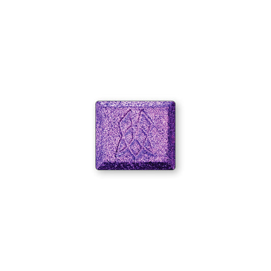 A single multichrome eyeshadow in colour S.C.U.B.A on a white background. A slate grey base, subtly shifting indigo-violet-peach with hints of yellow.
