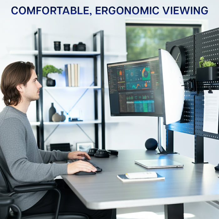 Person sitting at a desk with a computer setup featuring an ultrawide monitor mounted to a pegboard, emphasizing comfortable ergonomic viewing.