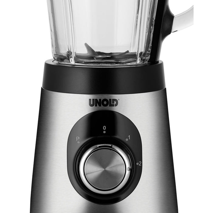 Nahaufnahme der Edelstahlbasis des Unold Standmixers Edel mit einem großen Drehregler für mehrere Geschwindigkeiten und dem Boden des oben angebrachten Mixbehälters aus klarem Glas.