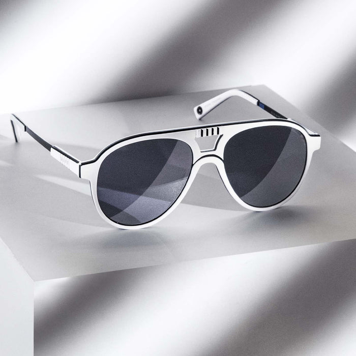 Angle shot of Star Wars x DIFF Stormtrooper sunglasses with arms open propped on top of white pedestal with a shadow casted over it