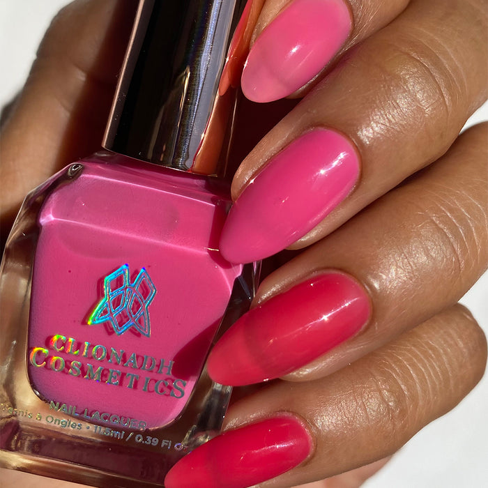 Close-up of nails painted with Stratus Nail Lacquer on medium skin tone. Hand is holding polish bottle.