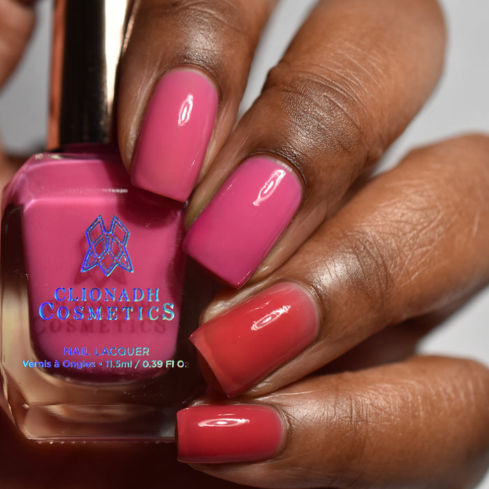 Close-up of nails painted with Stratus Nail Lacquer on deep skin tone. Hand is holding polish bottle.