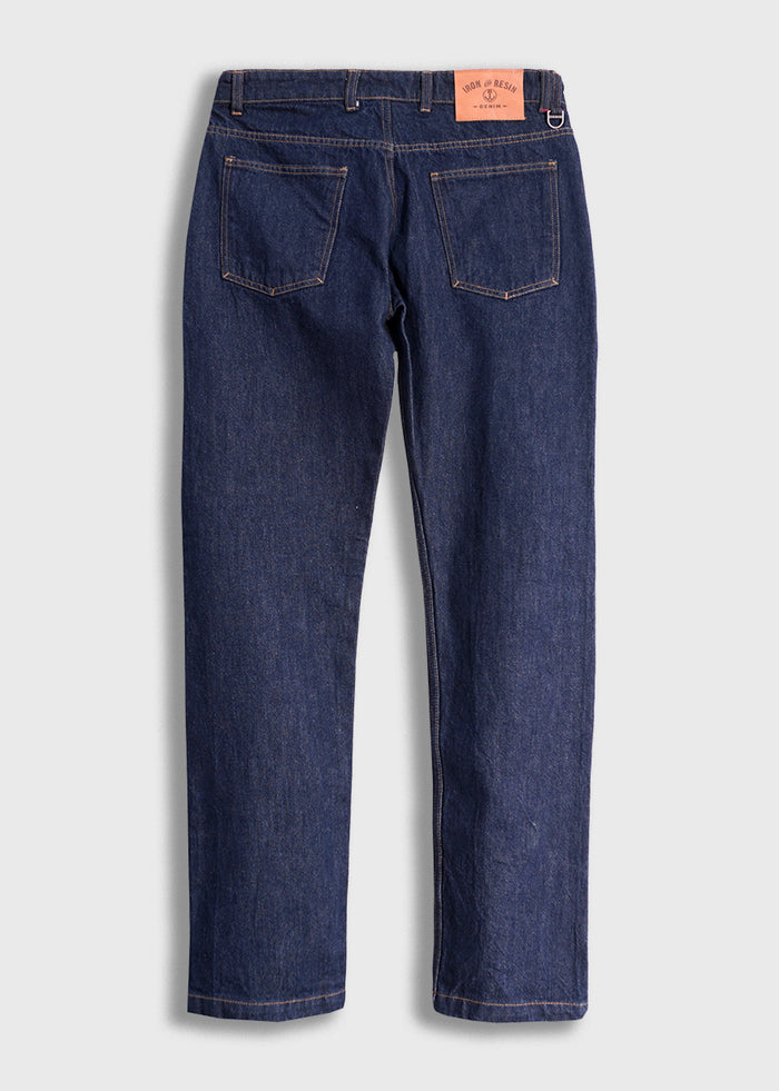 Back view of dark blue denim jeans with two rear pockets and a brown leather patch on the waistband, against a plain background.