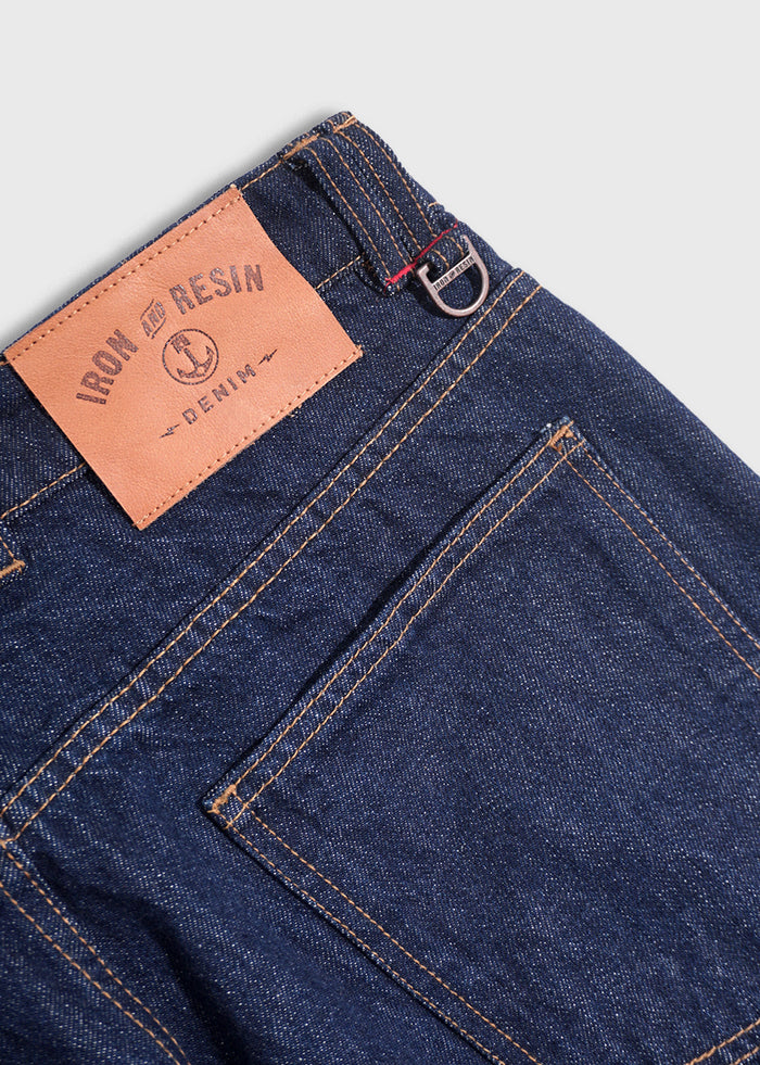 Close-up of Iron and Resin denim jeans with a leather patch and visible stitching, showcasing quality craftsmanship and design.