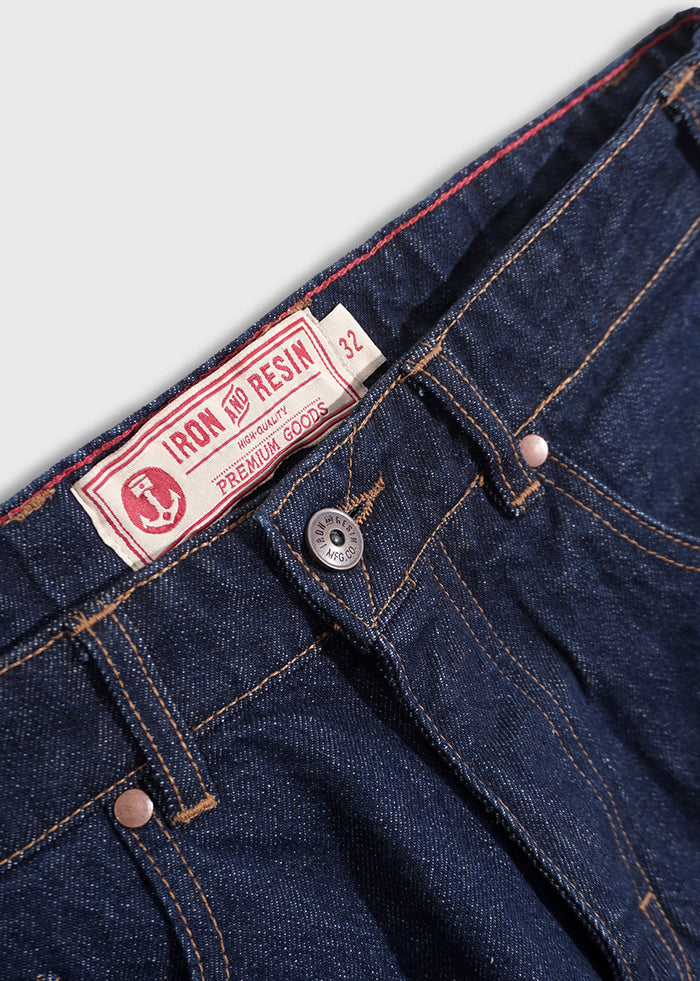 Close-up of Iron and Resin jeans with a red label and button detail, showcasing premium denim quality and craftsmanship.